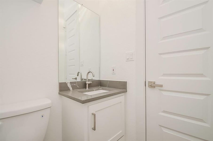 View of the powder room featuring a beautiful vanity with quartz tops.