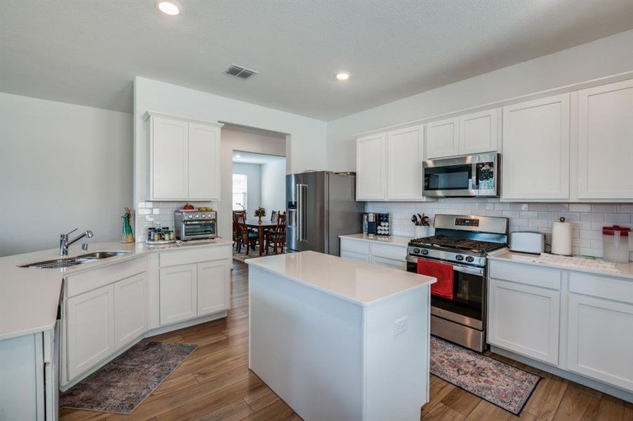 Kitchen featuring white cabinets, light hardwood / wood-style floors, appliances with stainless steel finishes, and sink