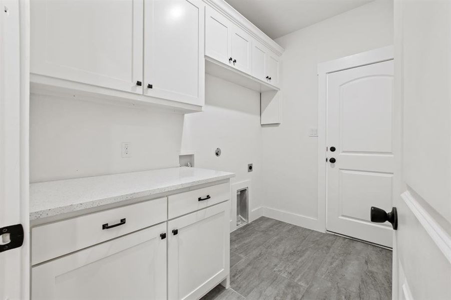 Clothes washing area with hookup for a washing machine, cabinets, light wood-type flooring, and hookup for an electric dryer