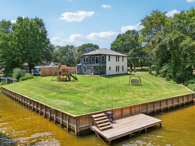 Dock area with a water view, a playground, and a lawn