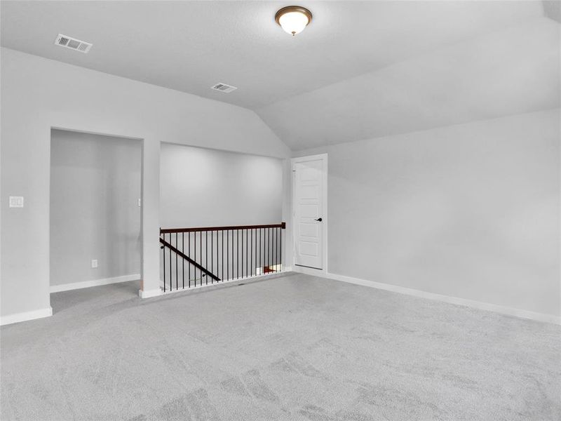 Another view of the upstairs game room featuring lofted ceiling and carpet. Quiet and isolated for loud play!