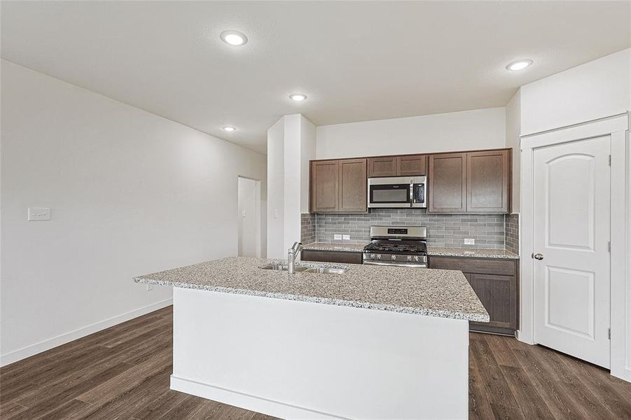 Kitchen featuring sink, appliances with stainless steel finishes, a kitchen island with sink, and dark hardwood / wood-style flooring