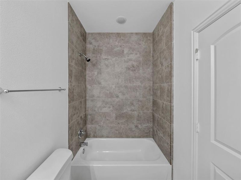 Bathroom featuring tiled shower / bath combo and toilet