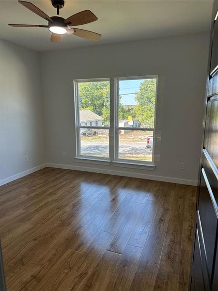 Empty room with ceiling fan and dark hardwood / wood-style flooring