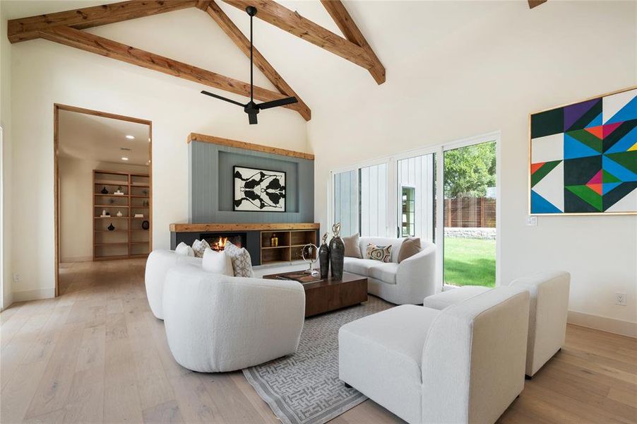 Living room featuring light wood-type flooring, built in features, ceiling fan, beamed ceiling, and high vaulted ceiling