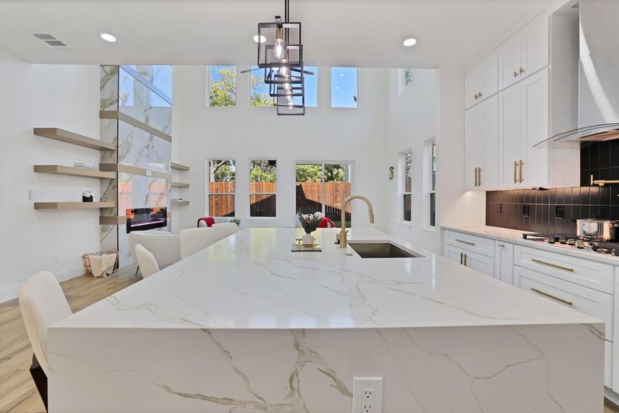 Kitchen featuring light stone counters, wall chimney exhaust hood, sink, light hardwood / wood-style floors, and white cabinetry