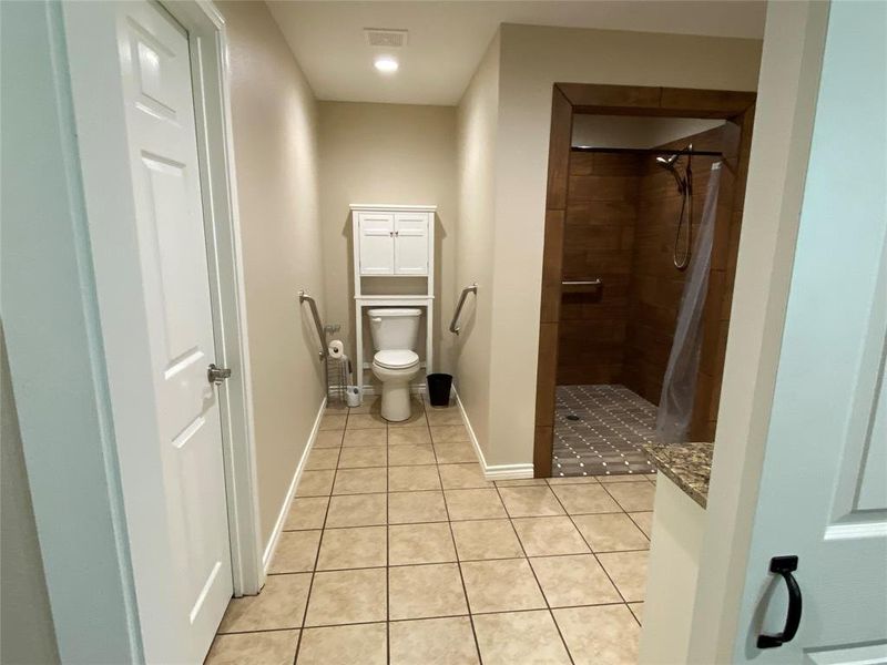 Primary Bathroom with tile floors, a tile shower, and toilet
