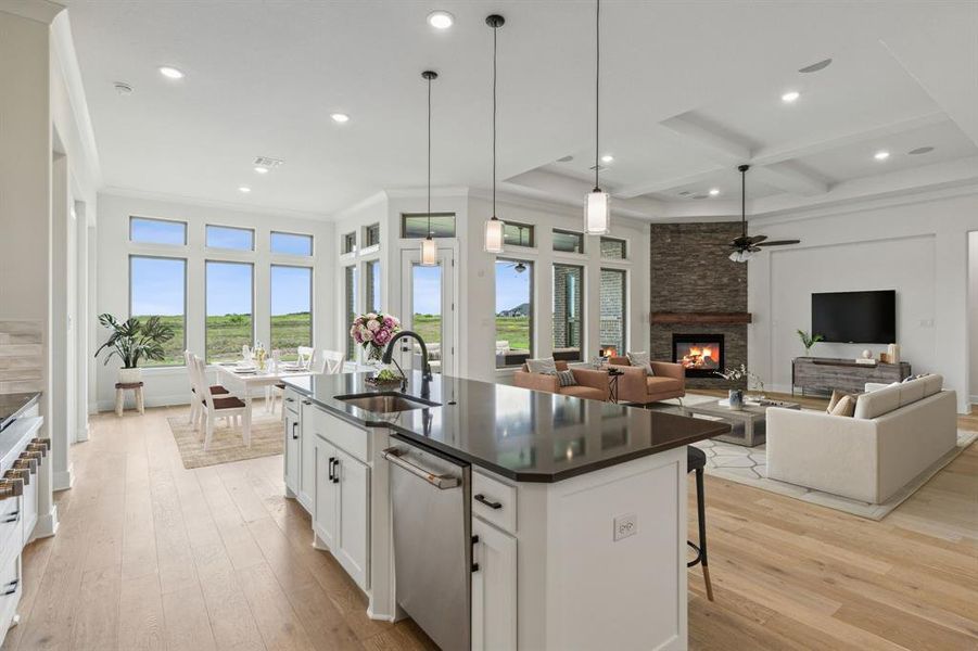 Kitchen featuring a stone fireplace, light hardwood / wood-style floors, an island with sink, ceiling fan, and white cabinets *VIRTUAL STAGING