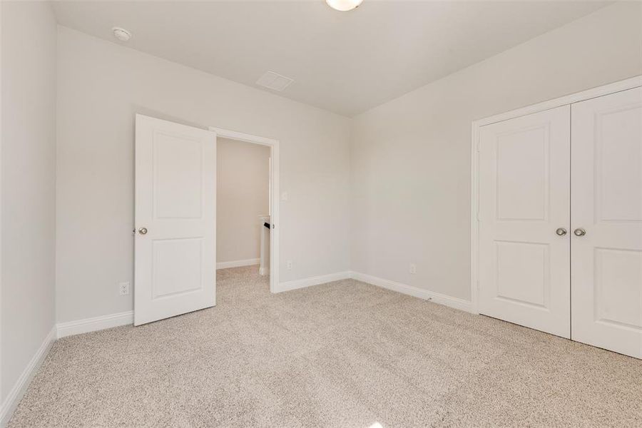 Unfurnished bedroom with light colored carpet and a closet