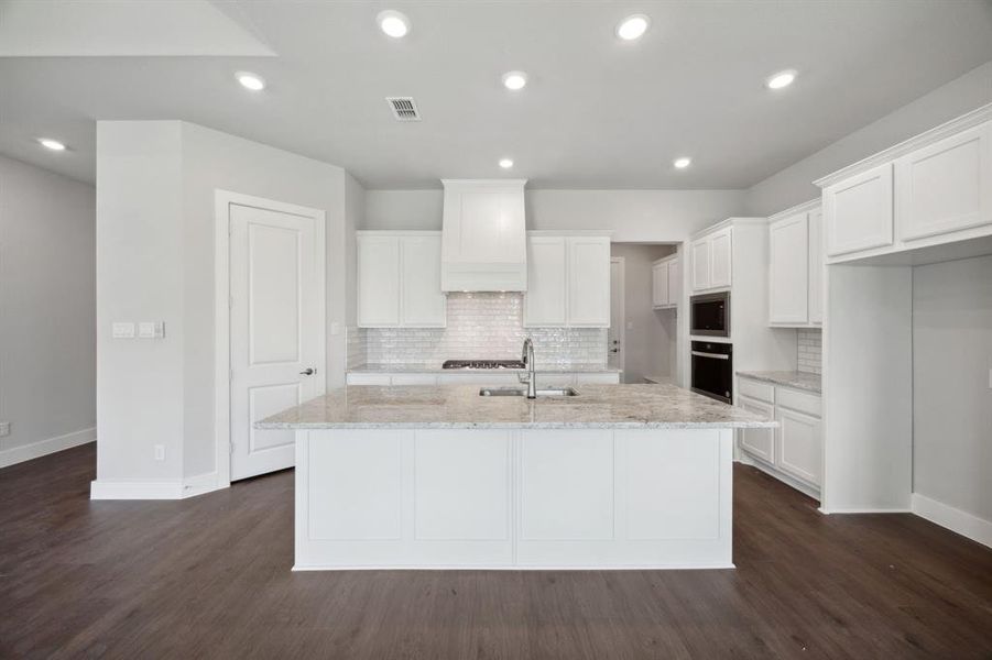 Kitchen featuring stainless steel appliances, backsplash, white cabinetry, dark wood-type flooring, and custom range hood