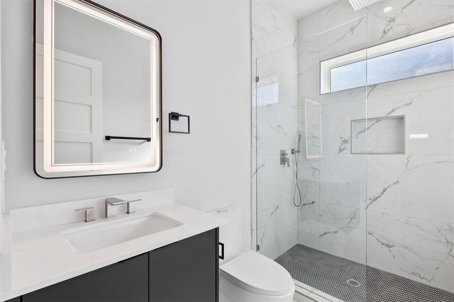 Bathroom with vanity, toilet, and tiled shower