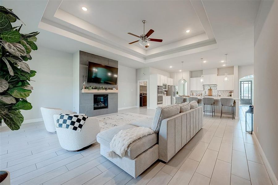 Living room features tile flooring, aceiling fan, high ceilings, and fireplace.