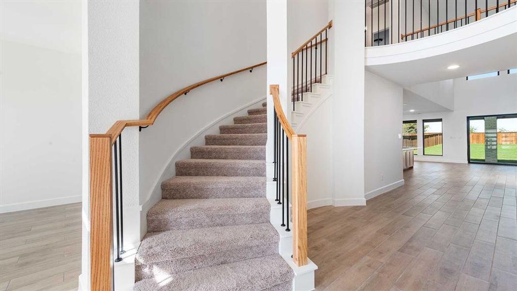 Stairs featuring hardwood / wood-style flooring and a high ceiling