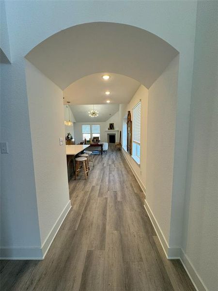 Hall with lofted ceiling, dark wood-type flooring, and an inviting chandelier