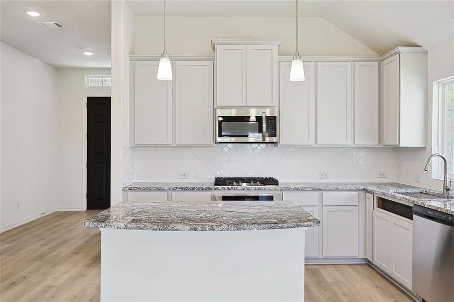 Kitchen featuring appliances with stainless steel finishes, backsplash, light hardwood / wood-style floors, and white cabinetry