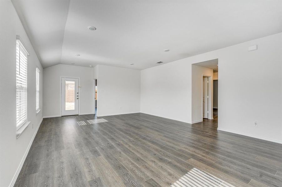 Empty room featuring lofted ceiling and dark hardwood / wood-style flooring