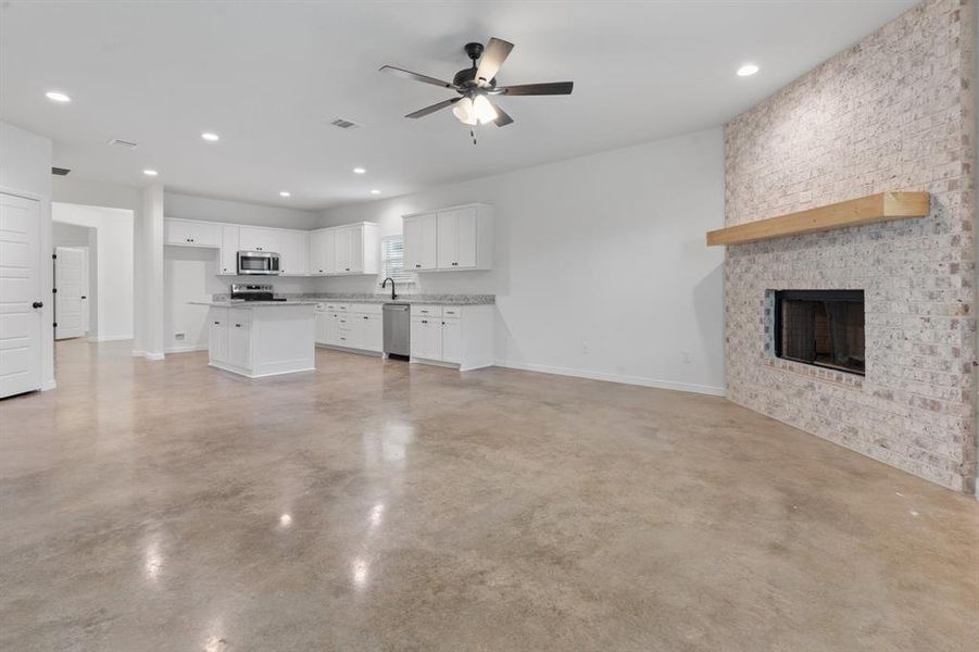 Unfurnished living room featuring a fireplace and ceiling fan