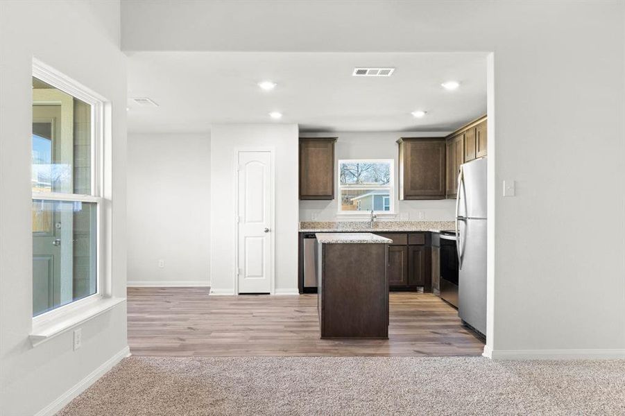 Kitchen featuring dark brown cabinets, light hardwood / wood-style flooring, appliances with stainless steel finishes, and a kitchen island