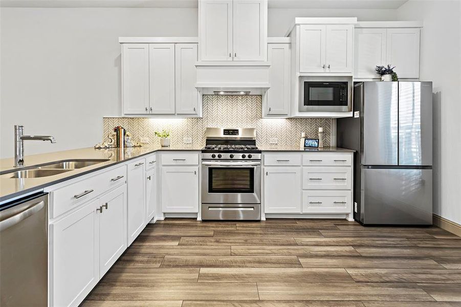 Kitchen with appliances with stainless steel finishes, white cabinetry, and sink