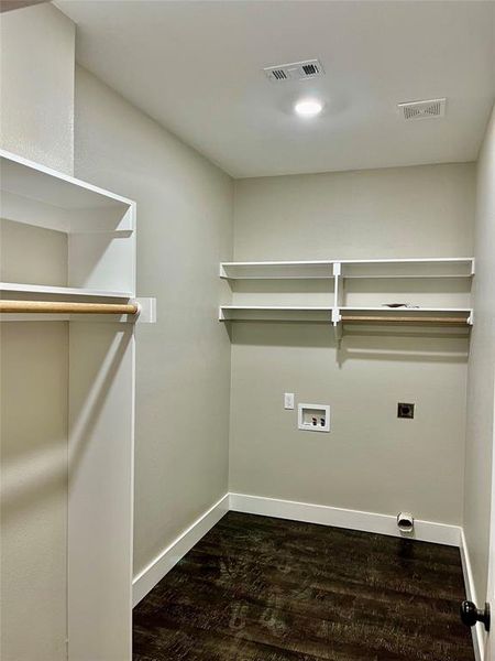 Clothes washing area with dark wood-type flooring, electric dryer hookup, and washer hookup