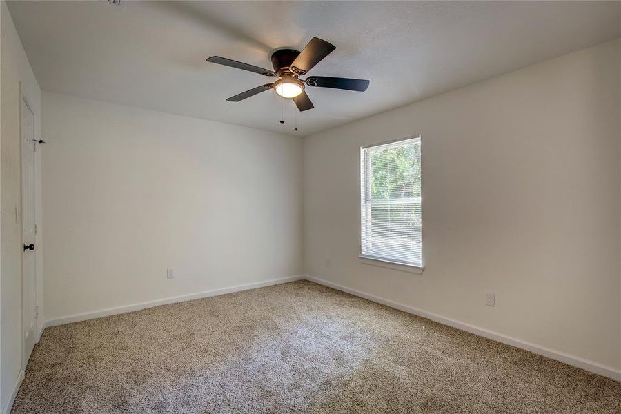Third room with carpet floors and ceiling fan