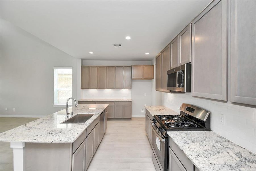 Culinary haven, featuring granite counter tops and stainless steel appliances (to be installed). Sample photo of completed home with similar floor plan. Actual colors and selections may vary.