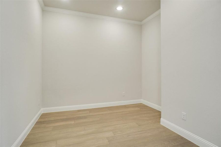 Empty room with light hardwood / wood-style floors and crown molding