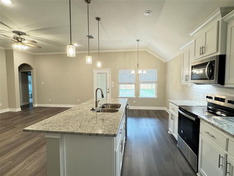 Kitchen with decorative backsplash, dark wood-type flooring, appliances with stainless steel finishes, and sink