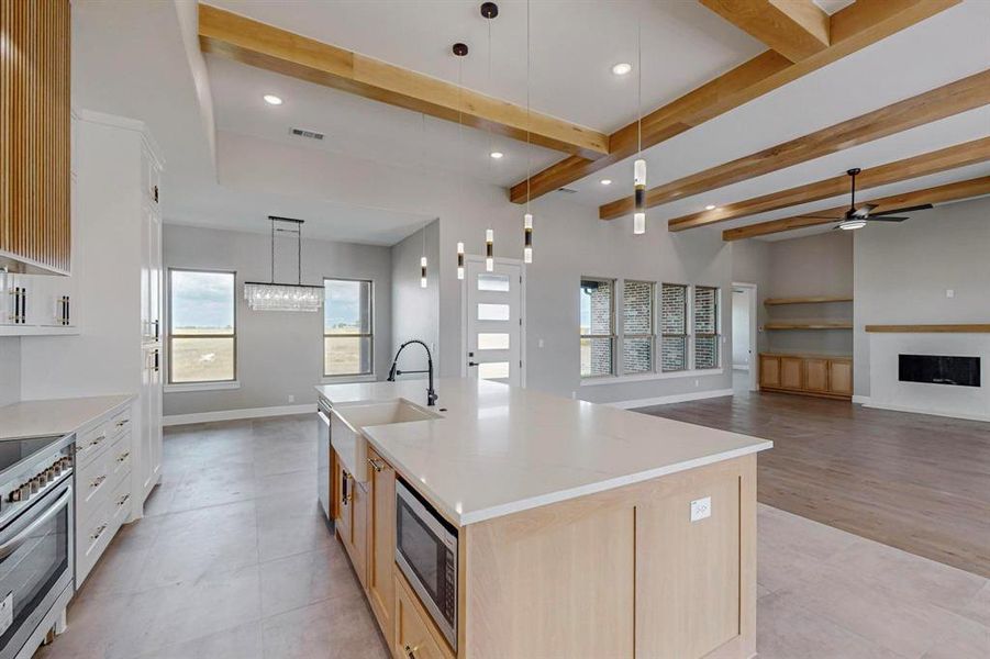 Kitchen featuring pendant lighting, beamed ceiling, a large island, stainless steel appliances, and light hardwood / wood-style floors