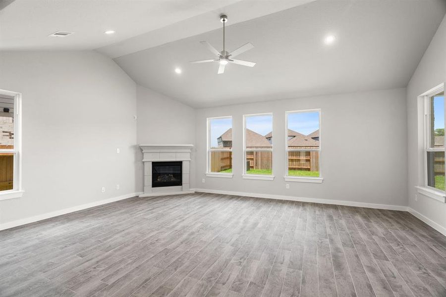 Family room flooded with natural light through the expansive windows.  The premium tile flooring adds a touch of luxury to the space, creating the perfect setting for relaxing moments and cherished gatherings with loved ones Sample photo, actual color and selections may vary.