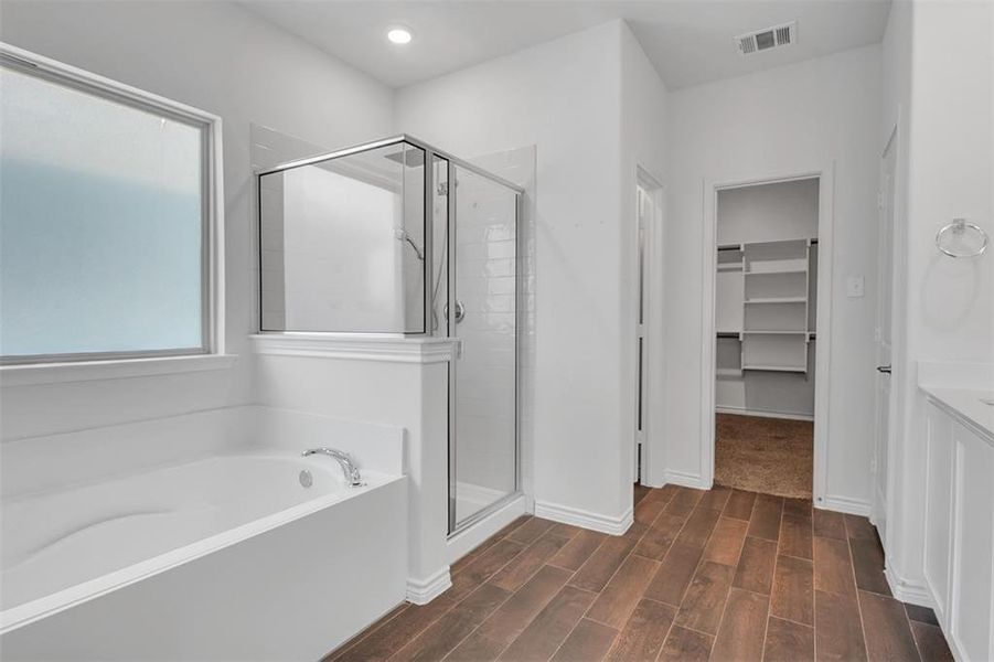 Master Bathroom with separate shower and tub and hardwood / wood-style flooring