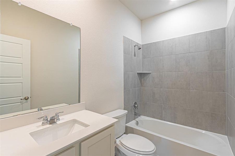 Full bathroom featuring toilet, tiled shower / bath combo, and vanity