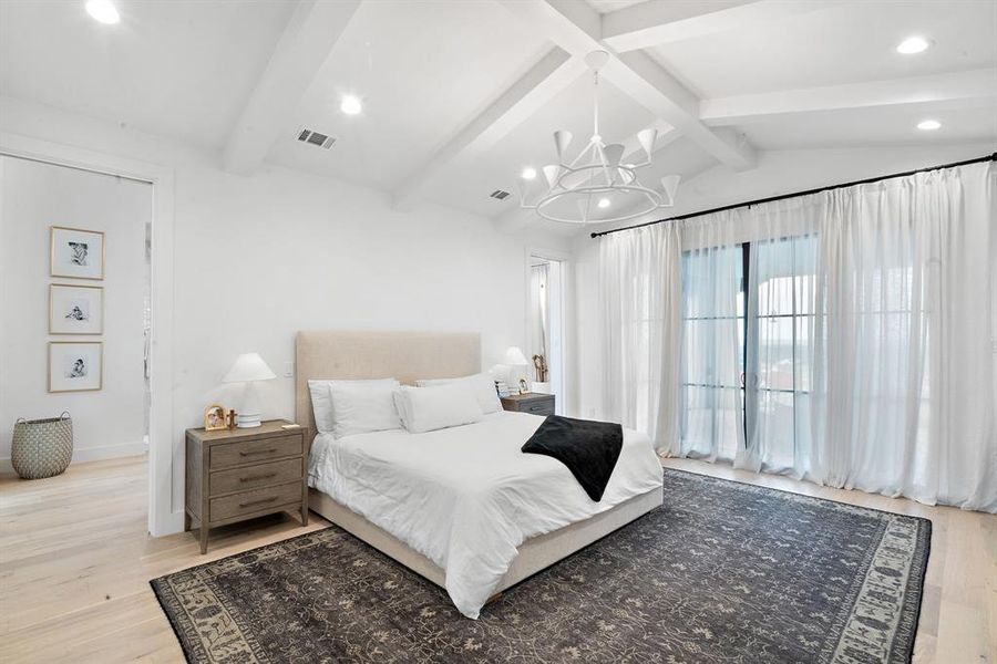 Bedroom with light hardwood / wood-style floors, vaulted ceiling with beams, and an inviting chandelier