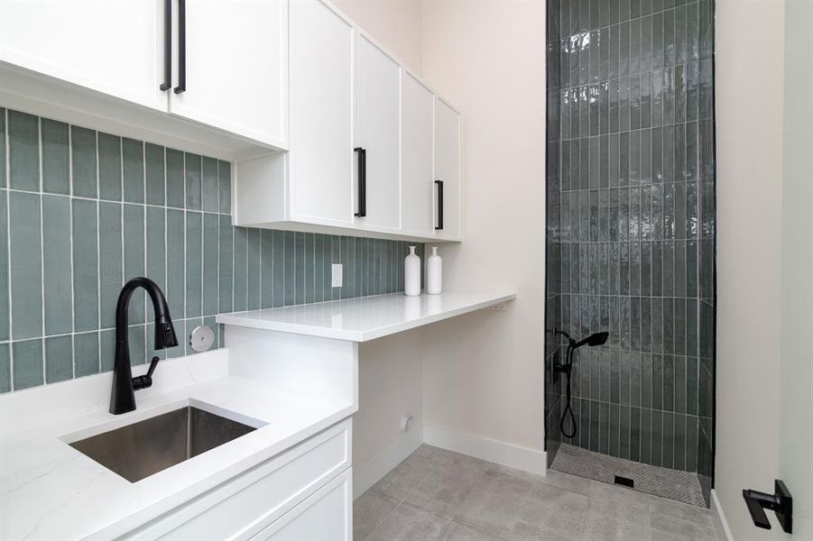 Kitchen with sink, white cabinetry, light tile flooring, and light stone countertops