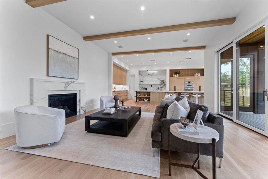 The open concept family room boasts elegance and is anchored by the Calacatta fireplace. Notice the floor to ceiling sliding glass doors that effortlessly open to the outdoor space and allow for ample natural light.