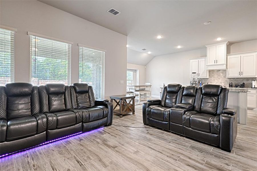 Living room with a wealth of natural light, vaulted ceiling, and light hardwood / wood-style flooring