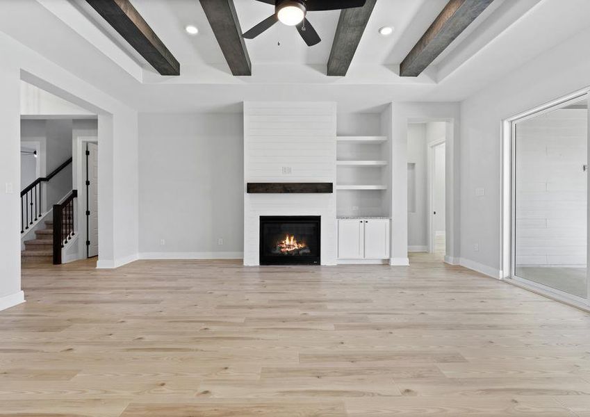 Living room has a fireplace and beam accents.