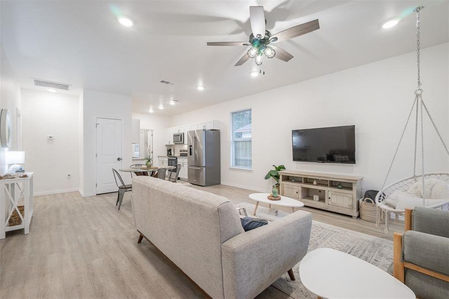 Living room with light hardwood / wood-style floors and ceiling fan