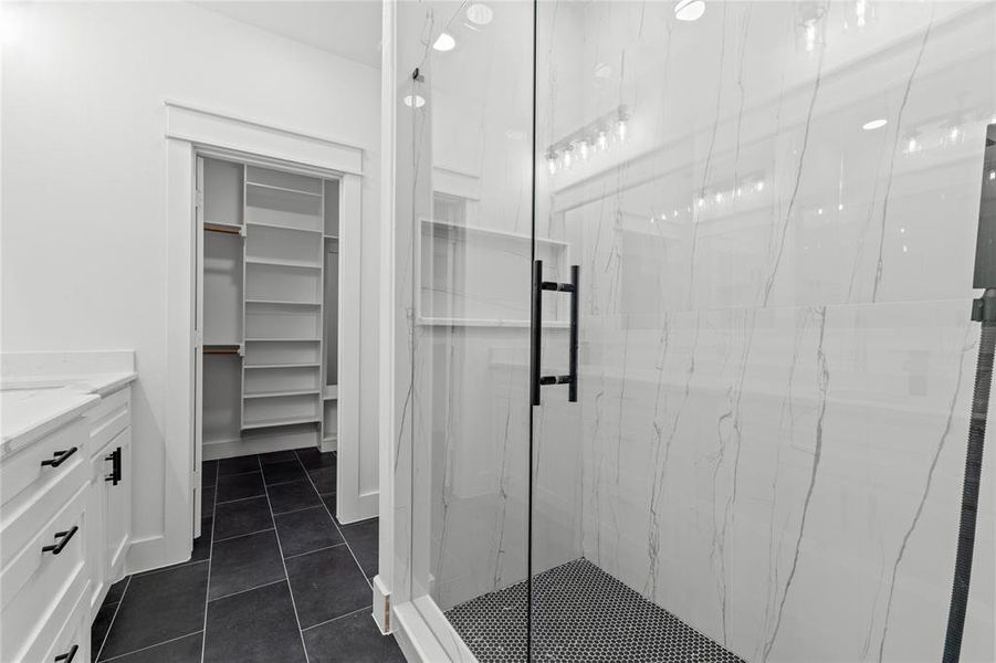 Bathroom featuring vanity, a shower with shower door, and tile patterned flooring