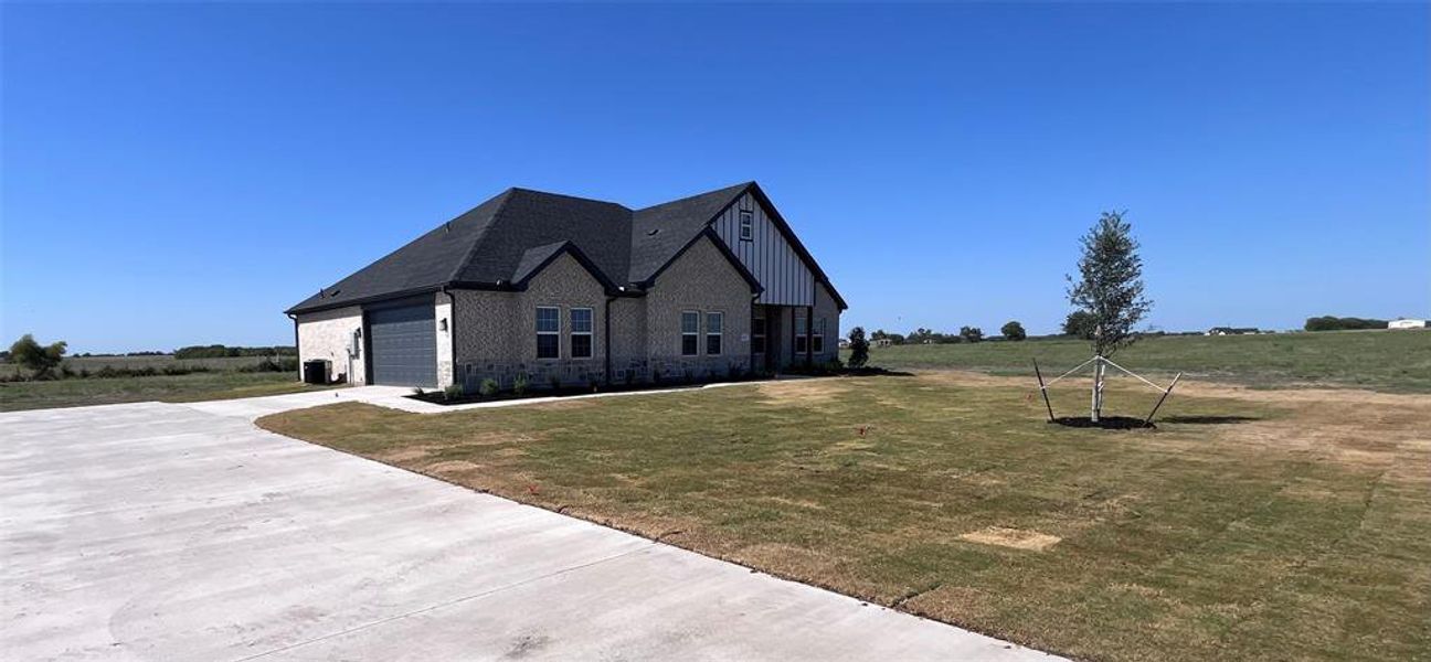 View of front facade with central AC unit, a front yard, and a garage