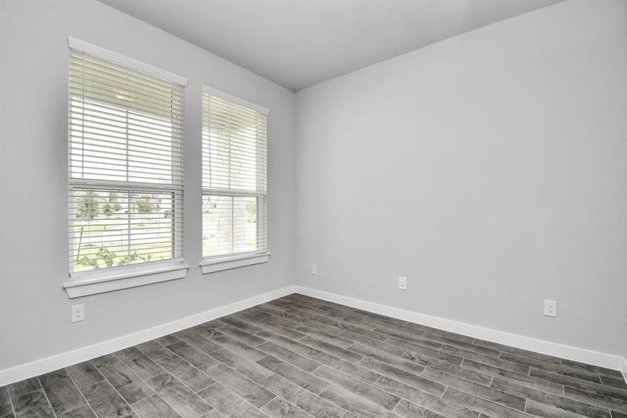 Experience the perfect blend of sophistication and warmth in this home office, boasting elegant wood-look tile flooring and flooded with natural light from expansive windows and French doors. Sample photo of completed home with similar floor plan. Actual colors and selections may vary.