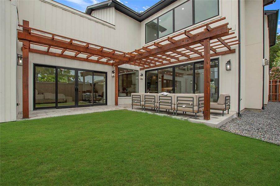 Rear view of house with a pergola, a lawn, and a patio area