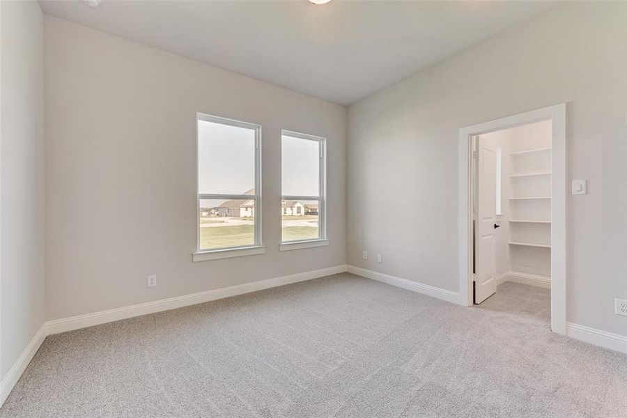 Unfurnished bedroom featuring light carpet, a closet, and a walk in closet