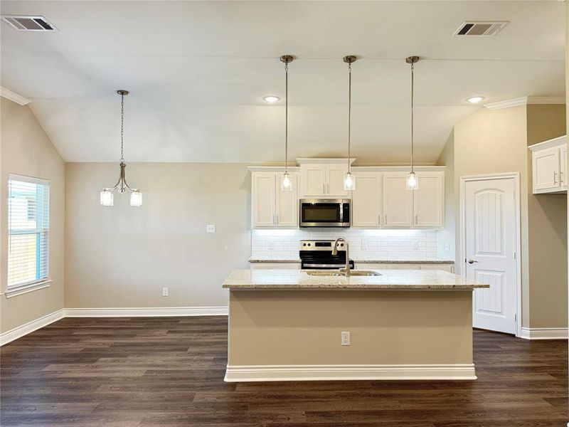 Kitchen featuring tasteful backsplash, white cabinets, vaulted ceiling, dark hardwood / wood-style floors, and appliances with stainless steel finishes