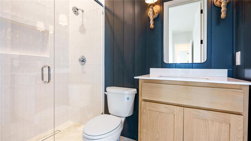 Bathroom featuring a shower with door, toilet, and vanity