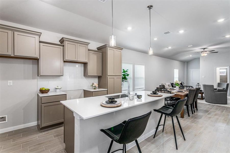 This stylish kitchen features modern cabinetry, sleek quartz countertops, and a spacious island that doubles as a breakfast bar. Equipped with top-of-the-line fixtures and a crisp subway tile backsplash, it combines functionality with a contemporary design. Ideal for both cooking and entertaining, the kitchen seamlessly flows into the open living and dining areas. **This image is from another Saratoga Home - Mockingbird floorplan.**