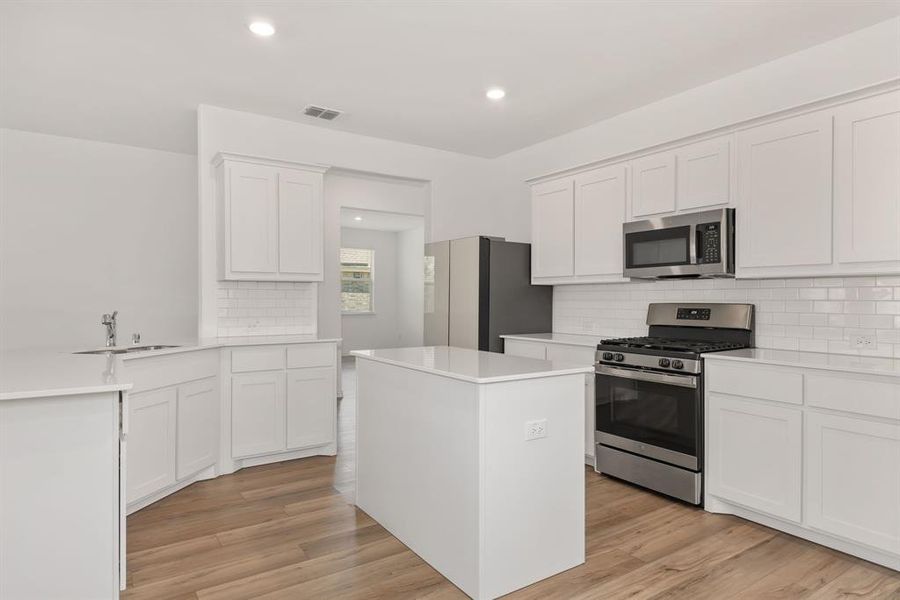 Kitchen featuring sink, light hardwood / wood-style flooring, white cabinets, and appliances with stainless steel finishes