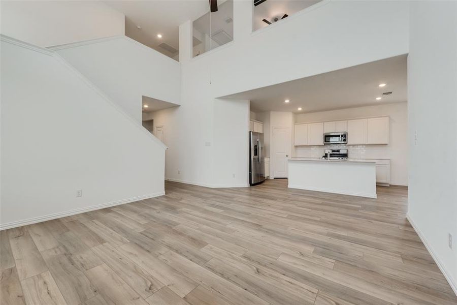 Unfurnished living room featuring a high ceiling and light hardwood / wood-style floors