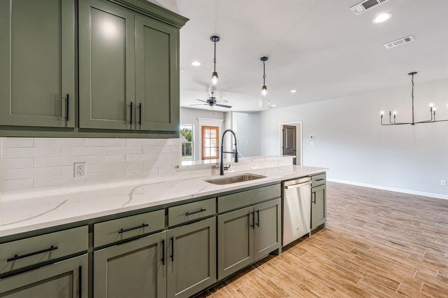 Kitchen with light hardwood / wood-style flooring, ceiling fan with notable chandelier, hanging light fixtures, and stainless steel dishwasher