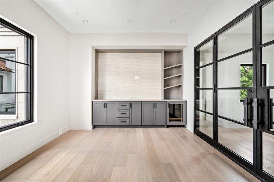 The second-floor game room impresses with grand Cantera doors, an expansive built-in entertainment console complete with a beverage cooler, and an abundance of natural light. This versatile space also serves perfectly as a stylish home office.